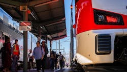 people pass an electric train at a caltrain station people pass an electric train at a caltrain station