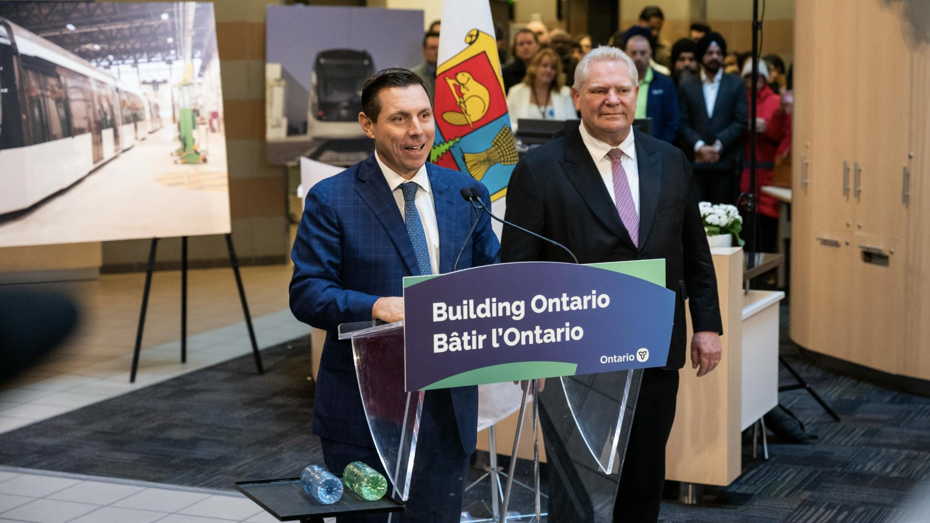Brampton city officials stand at podium with project renderings in the background