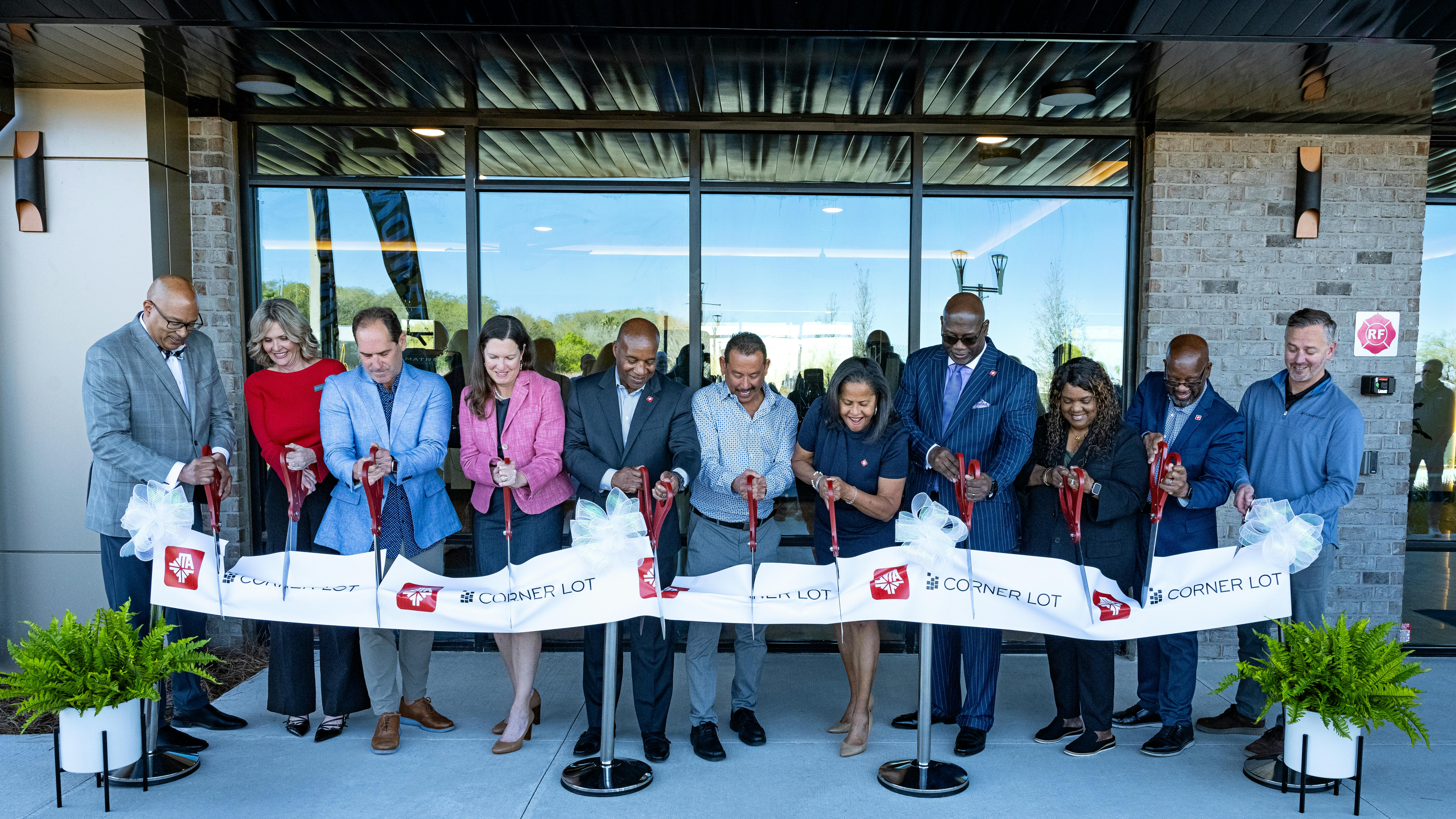 Line of people stand outside apartment building cutting ribbon
