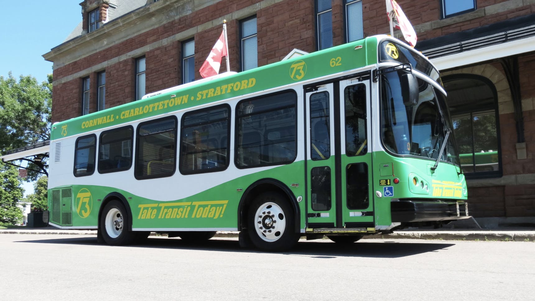 a green and white wrapped bus from T3 Transit sits on the street