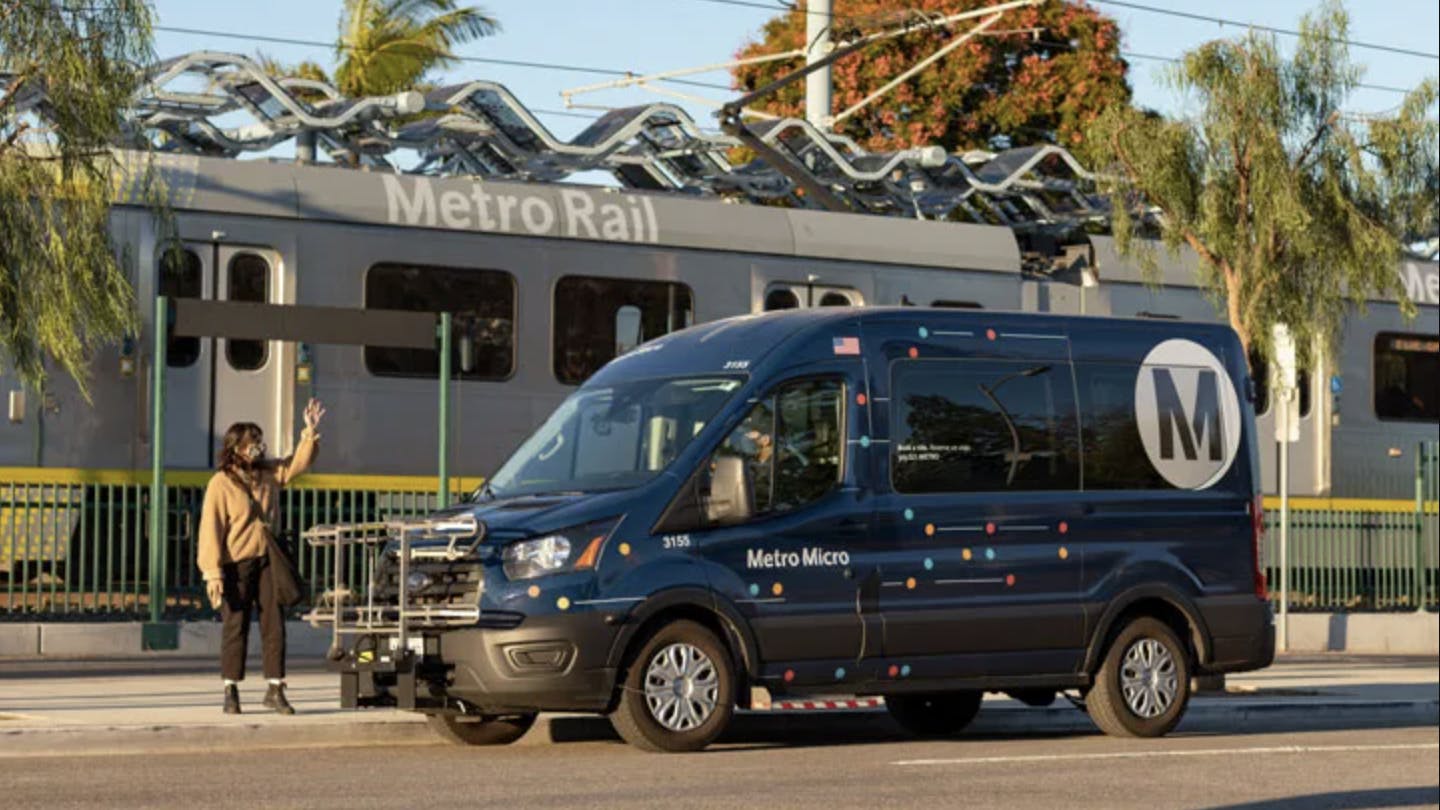 person waits on curb as metro micro van pulls up outside rail station