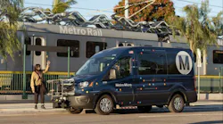 person waits on curb as metro micro van pulls up outside rail station