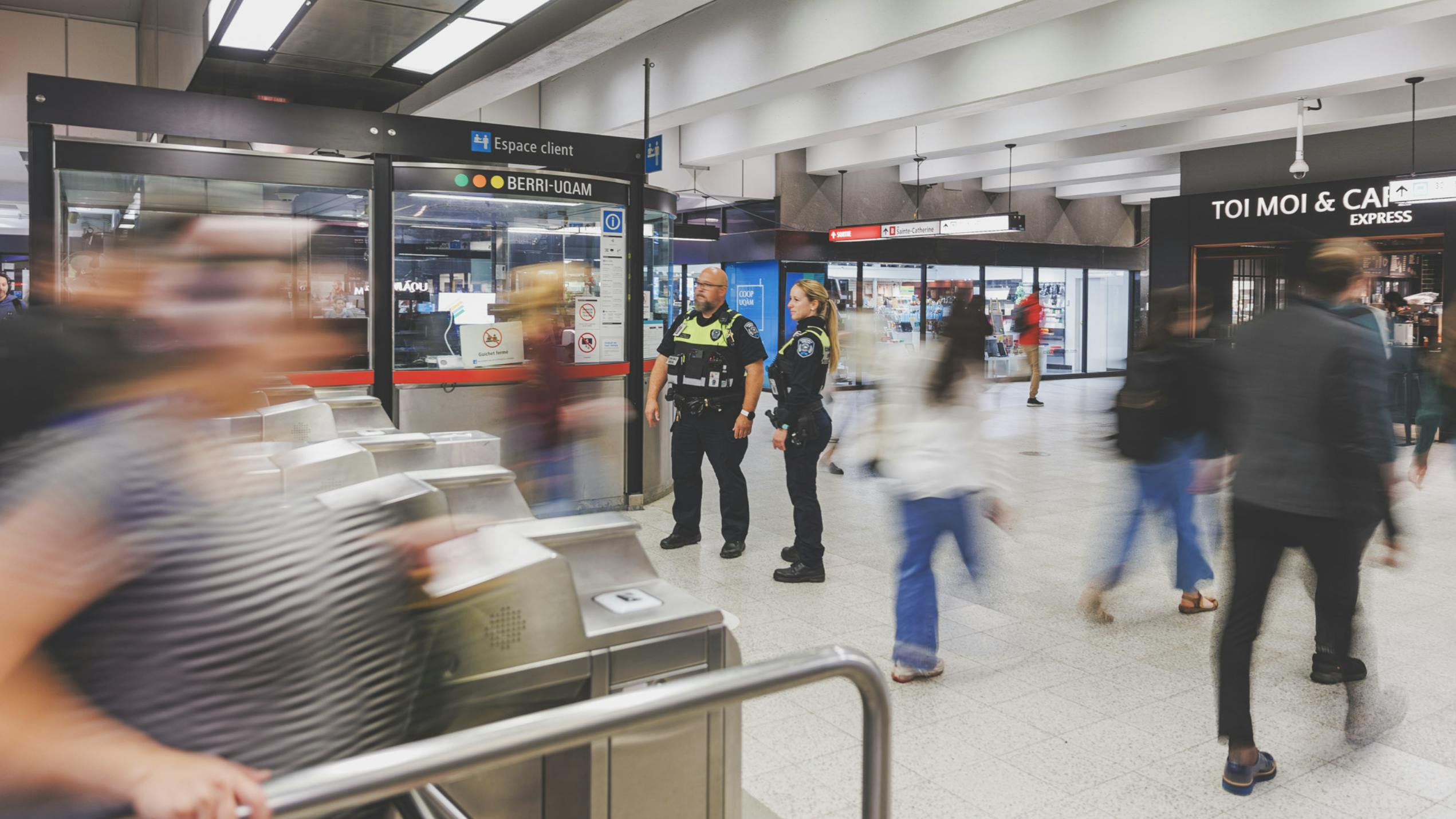 two officers stand outside fare gates in a STM's Metro station