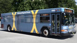 PRT grey bus drives down the street on sunny day PRT grey bus drives down the street on sunny day