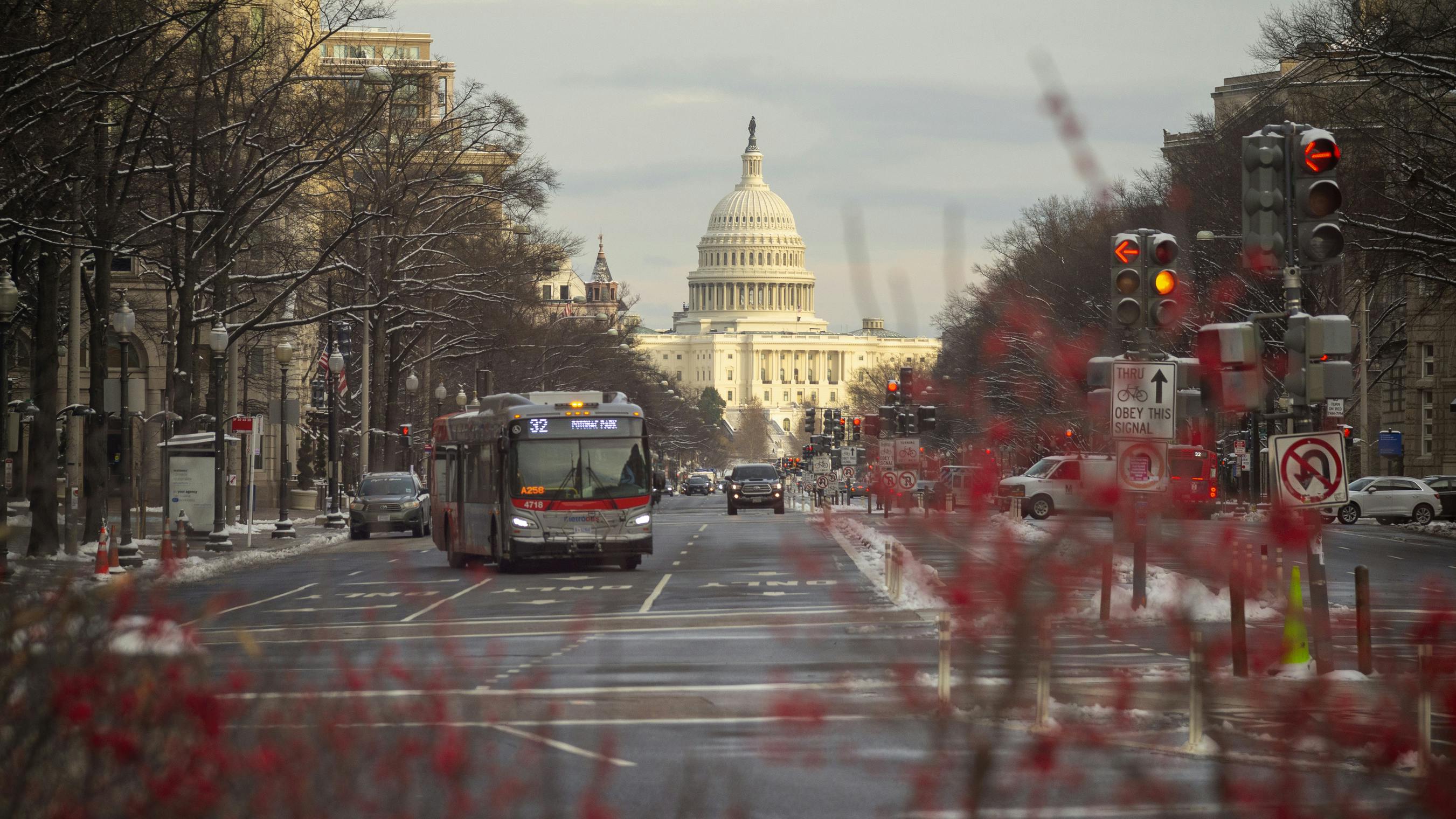 bus drives down road in D.C. with capitol building behind