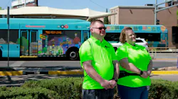 two ABQ Ride ambassadors in neon green shirts pose in front of a bus