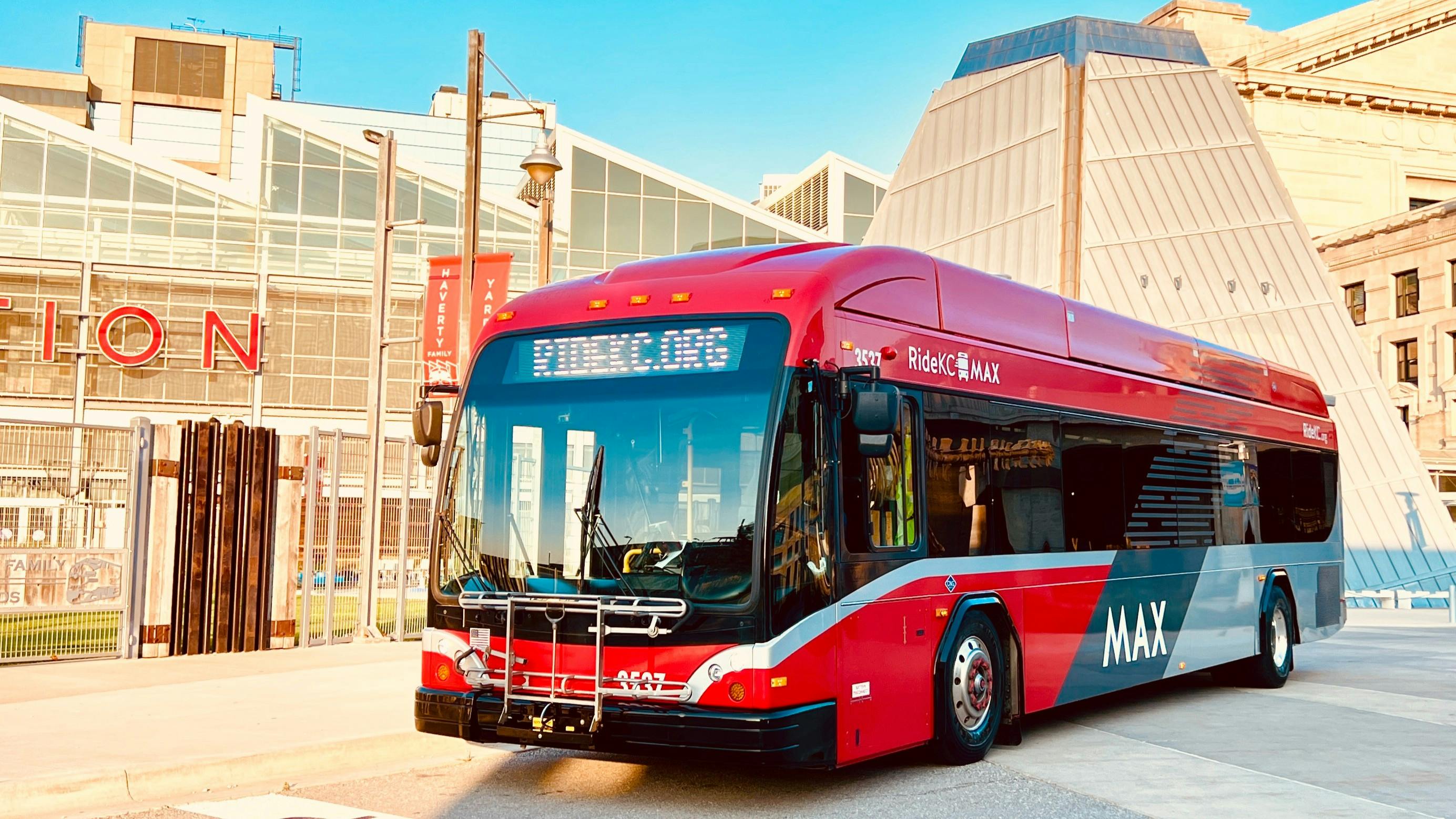 a red MAX-branded pulls out in front of a building in downtown