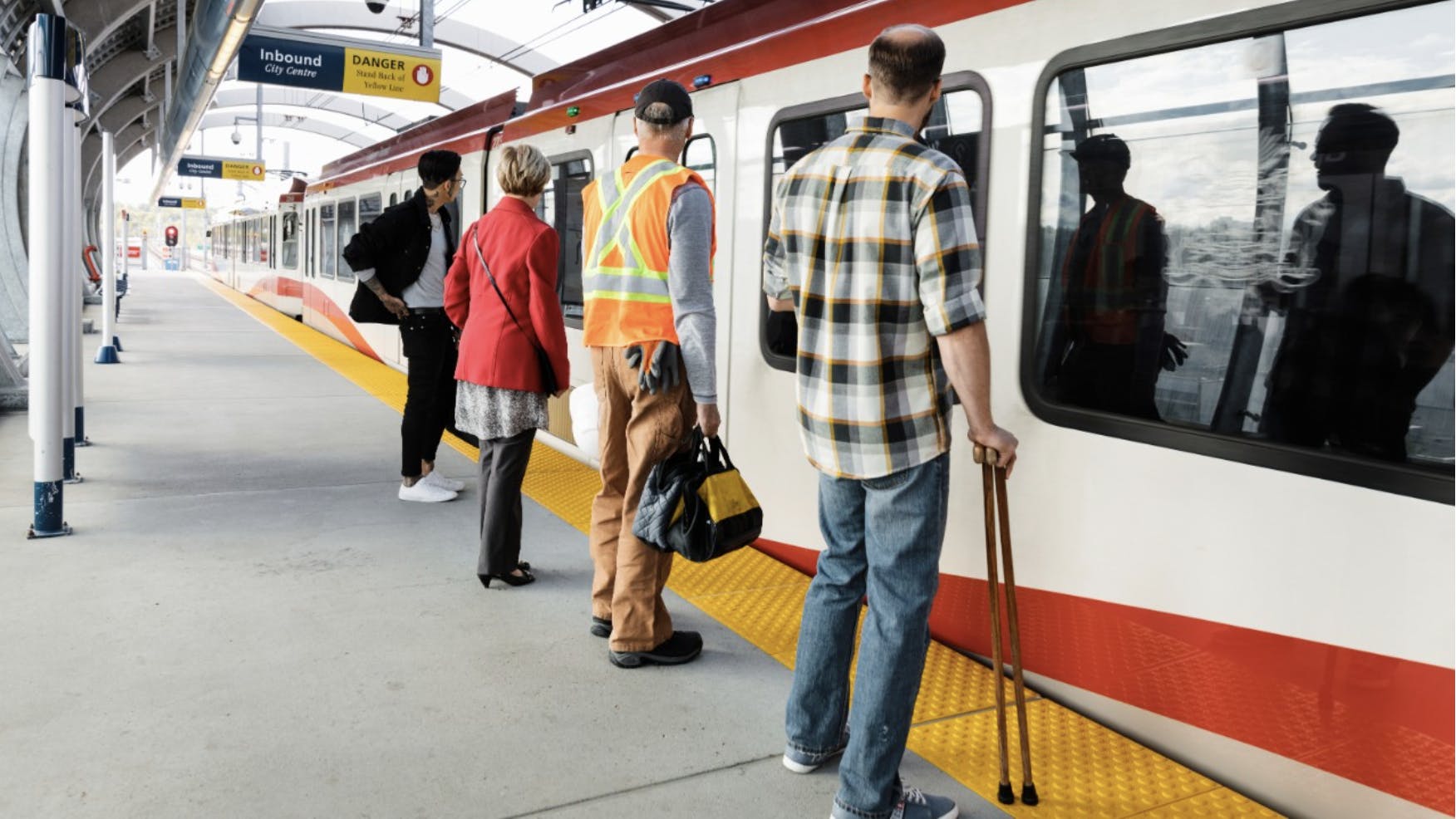people wait to board a CTrain on a platform