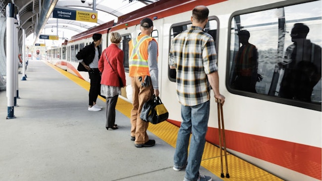 people wait to board a CTrain on a platform