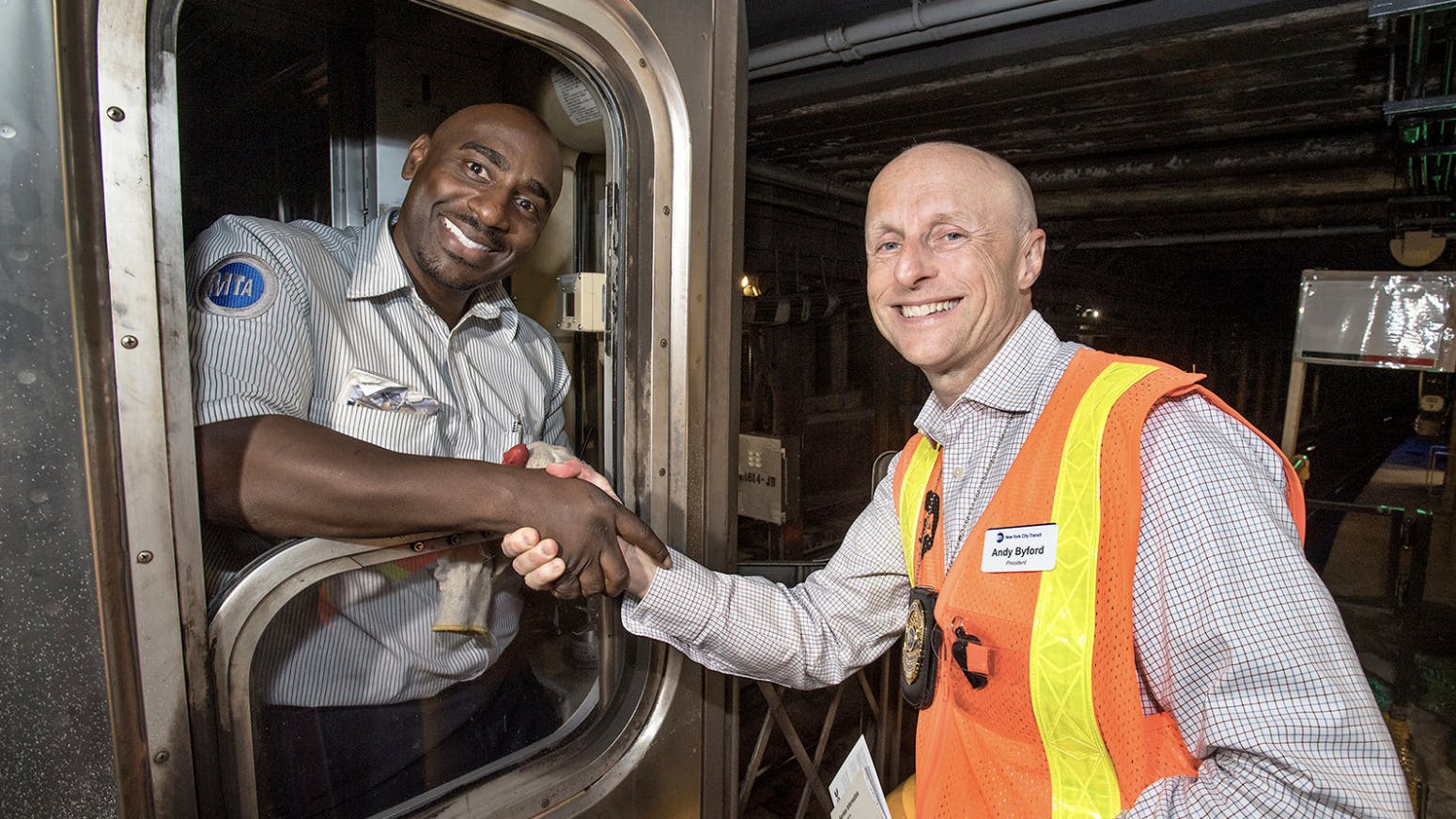 Andy Byford shakes hand with a subway operator standing inside a rail car