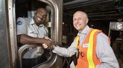 Andy Byford shakes hand with a subway operator standing inside a rail car