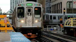 Chicago Transit Authority train approaches a passenger platform after a tight curve. A sign warns of the danger of trespass onto the tracks.