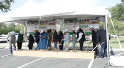 stakeholders stand in a line in front of a VIA Green Line banner and dig shovels into a box of dirt