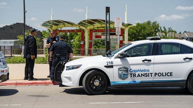 three patrol officers stand in front of capmetro transit police branded SUV