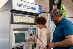a man and a woman stand in front of a Metrolink ticket vending machine to purchase a ticket a man and a woman stand in front of a Metrolink ticket vending machine to purchase a ticket