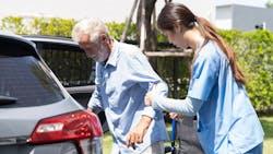 a health aid helps an older man into a car a health aid helps an older man into a car