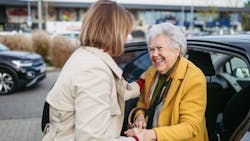 older woman shakes hand and smiles with a younger woman as she gets out of the car older woman shakes hand and smiles with a younger woman as she gets out of the car