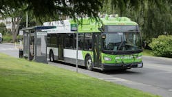 White and green BC Transit wrapped bus pulls over at a bus stop with a shelter and bench White and green BC Transit wrapped bus pulls over at a bus stop with a shelter and bench