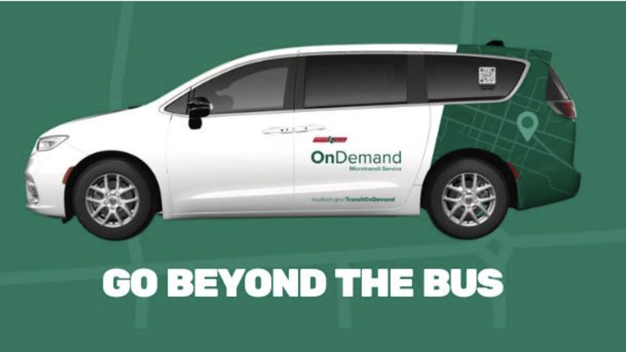 minivan with OnDemand Microtransit Service written on the side in green lettering with a green wrap around the back of the van