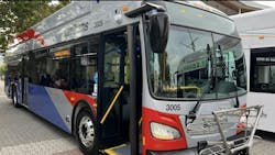 A SamTrans bus parks on the street under a tree A SamTrans bus parks on the street under a tree