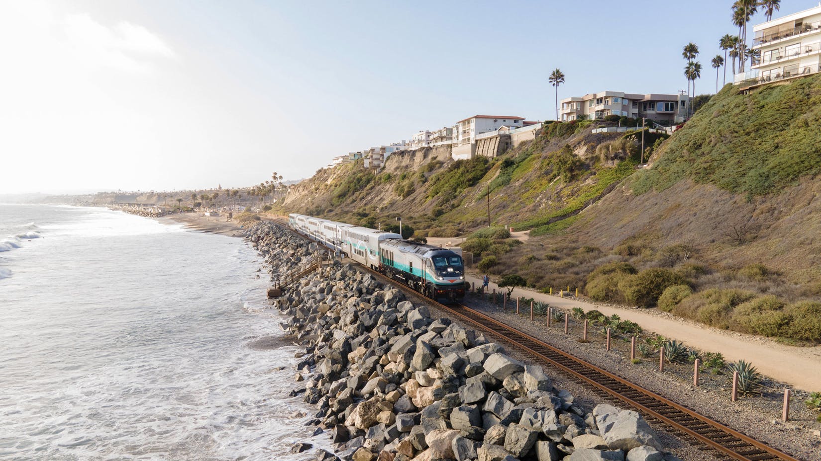 passenger train runs down the coastal corridor next to the ocean
