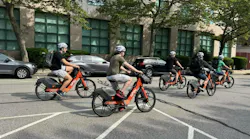 five people rides spin-branded bikes down a city street
