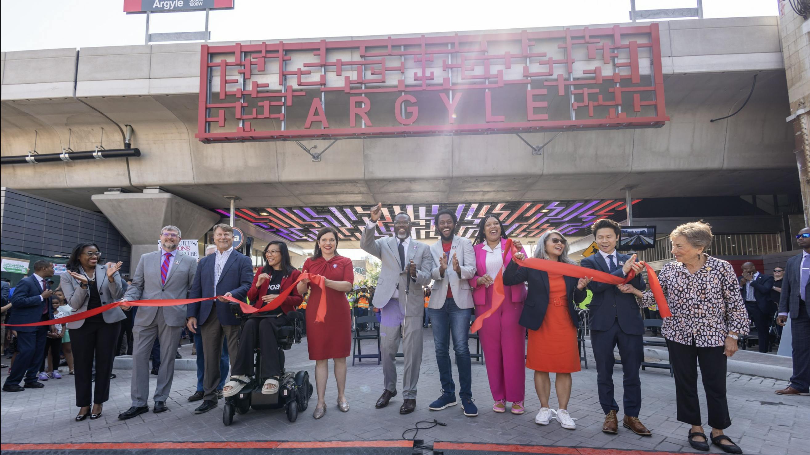 group of people stand in a line at ground level underneath the newly renovated Argyle red line station