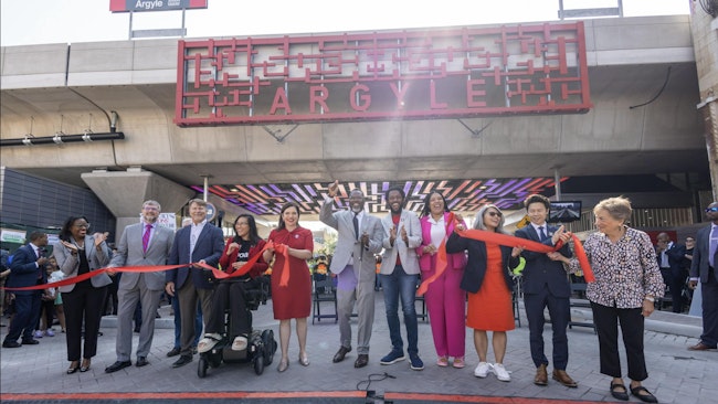 group of people stand in a line at ground level underneath the newly renovated Argyle red line station