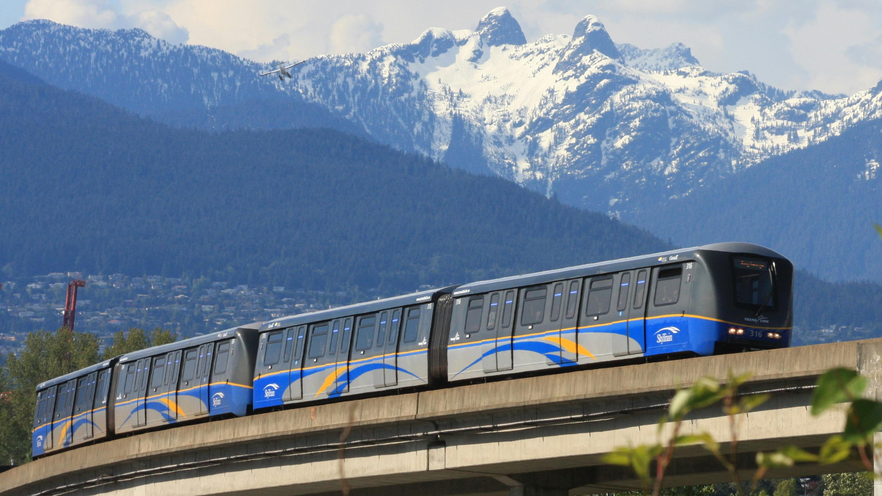 a SkyTrain on an elevated guideway with mountains in the back
