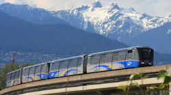 a SkyTrain on an elevated guideway with mountains in the back