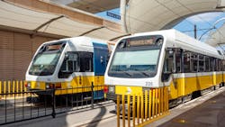 two DART light rail trains sit at a station under a canopy two DART light rail trains sit at a station under a canopy