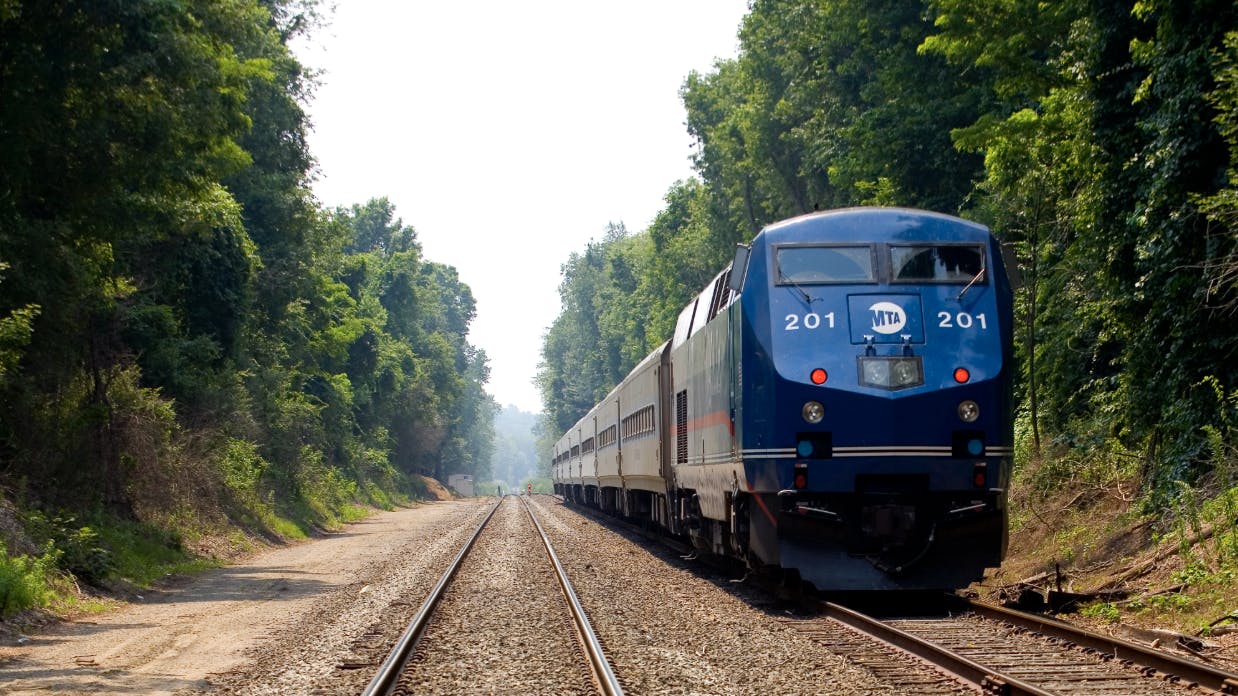 metro-north locomotive runs down track surrounded by trees