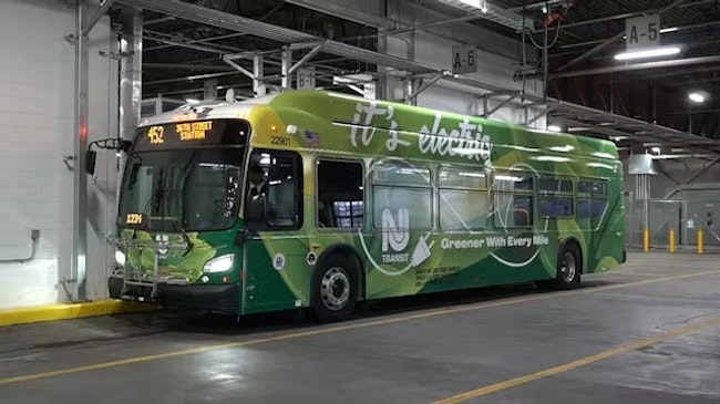 An electric NJ Transit bus sits parked with its lights on bearing 'it's electric' livery.