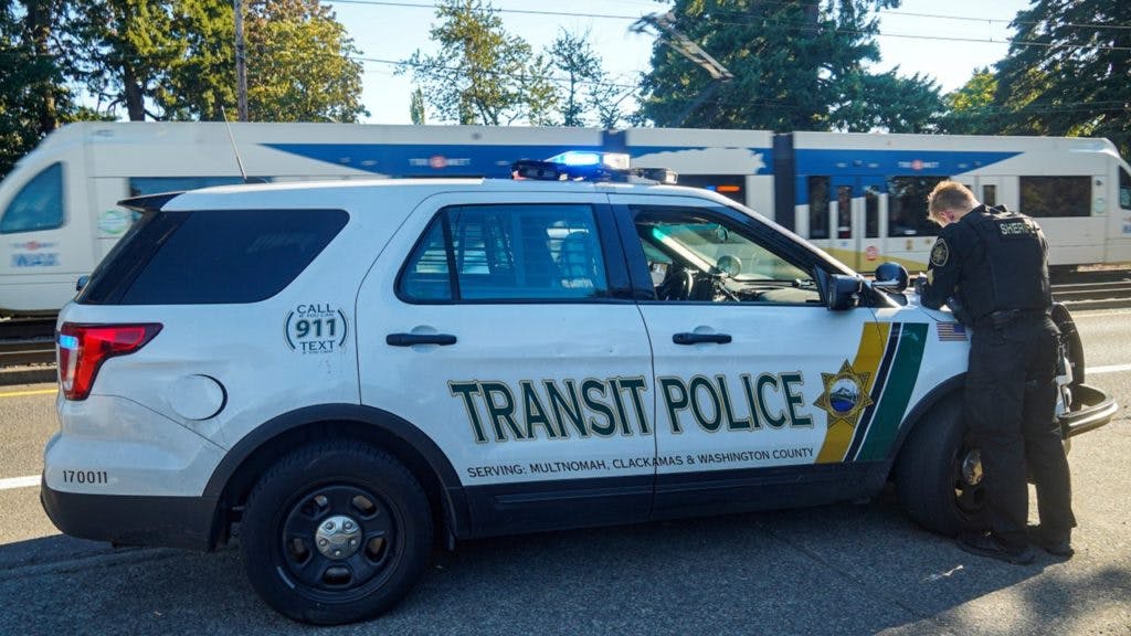 A transit police officer works over the hood of their cruiser.