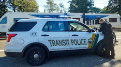 A transit police officer works over the hood of their cruiser.
