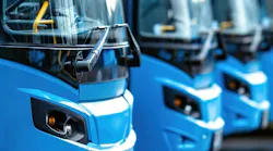 Buses sit in a line next to each other.