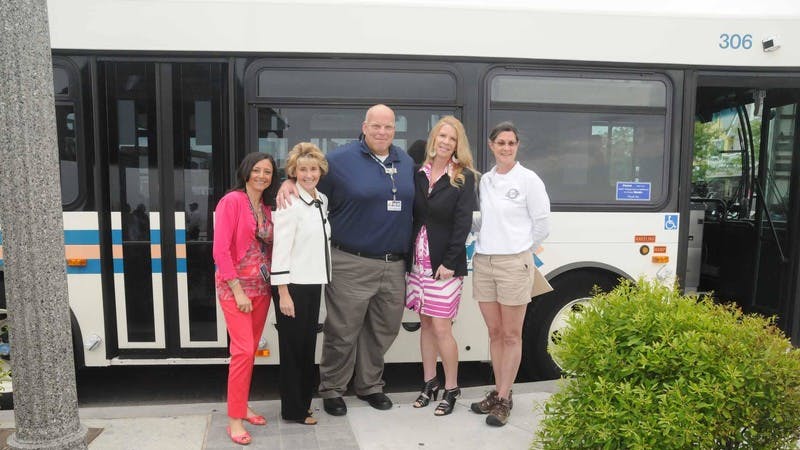a group of people stand posing in front of a bus outside