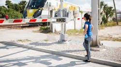 A girl standing at a railroad crossing. A girl standing at a railroad crossing.