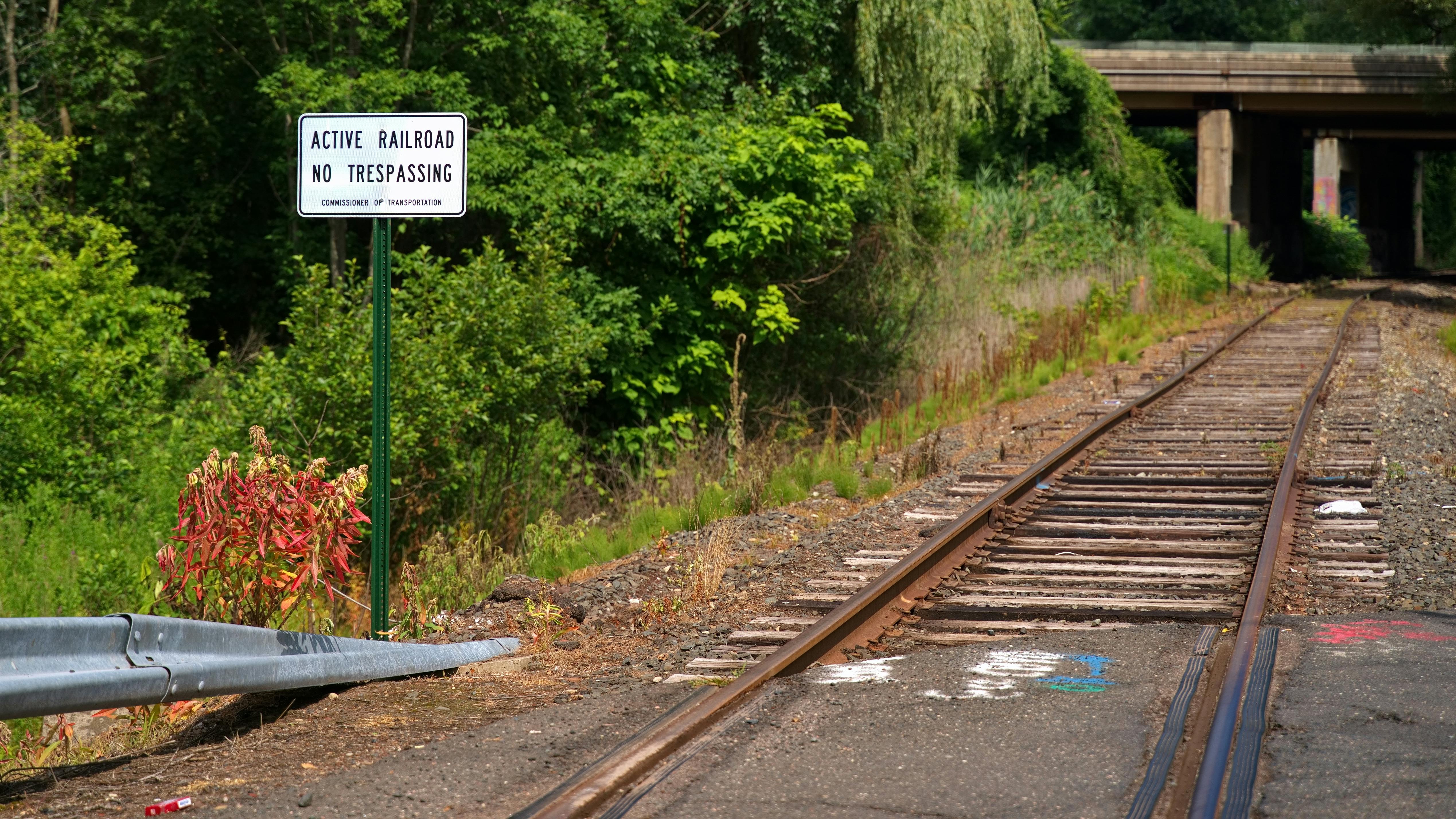 at-grade empty railroad crossing with sign that says no trespassing active railroad next to it