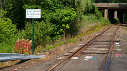 at-grade empty railroad crossing with sign that says no trespassing active railroad next to it