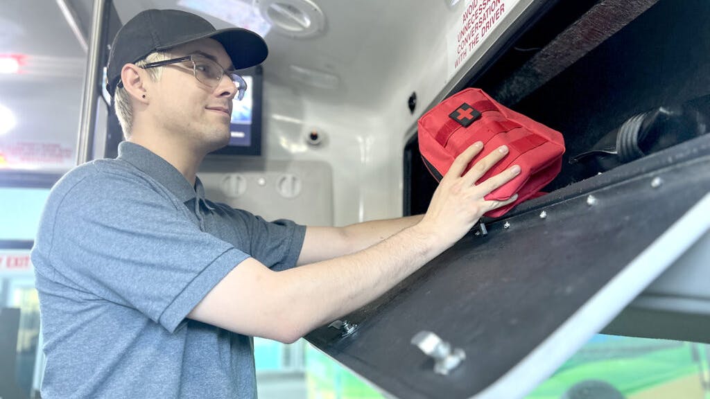 The image displays a man stocks a VVTA vehicle with NARCAN.