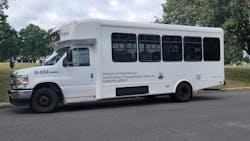 A white shuttle bus sits in a staging area. A white shuttle bus sits in a staging area.