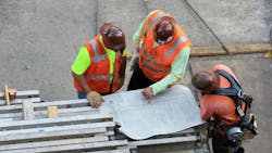 Three construction workers looking at construction drawing blueprint Three construction workers looking at construction drawing blueprint