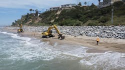 An excavator moves sand on a beach. An excavator moves sand on a beach.