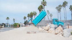 A truck dumps sand onto the beach. A truck dumps sand onto the beach.