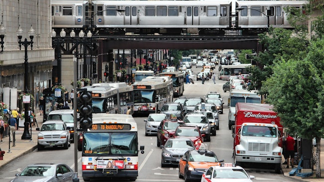 CTA buses drive down the street through heavy traffic.
