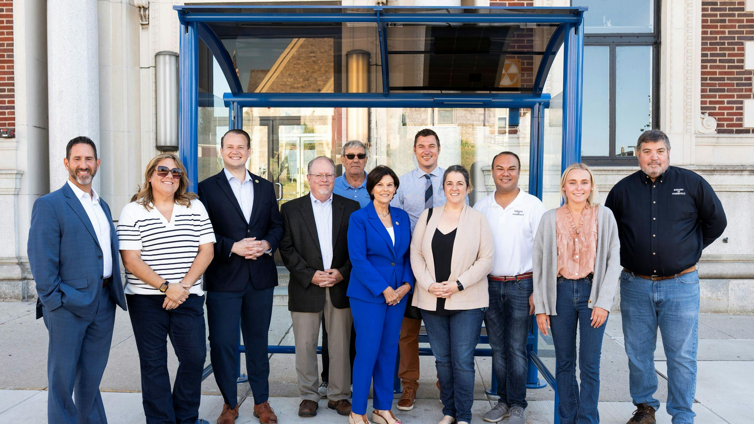 City leaders stand posed in front of the new bus shelter.