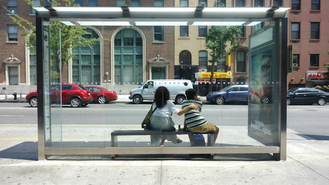 Two people waiting at a bus stop on 14th Street, in Manhattan.