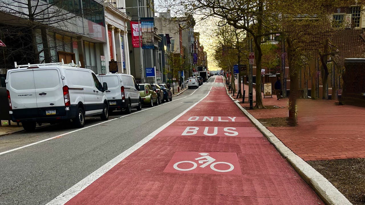 The image shows a long shot of a new red-painted bus lane.