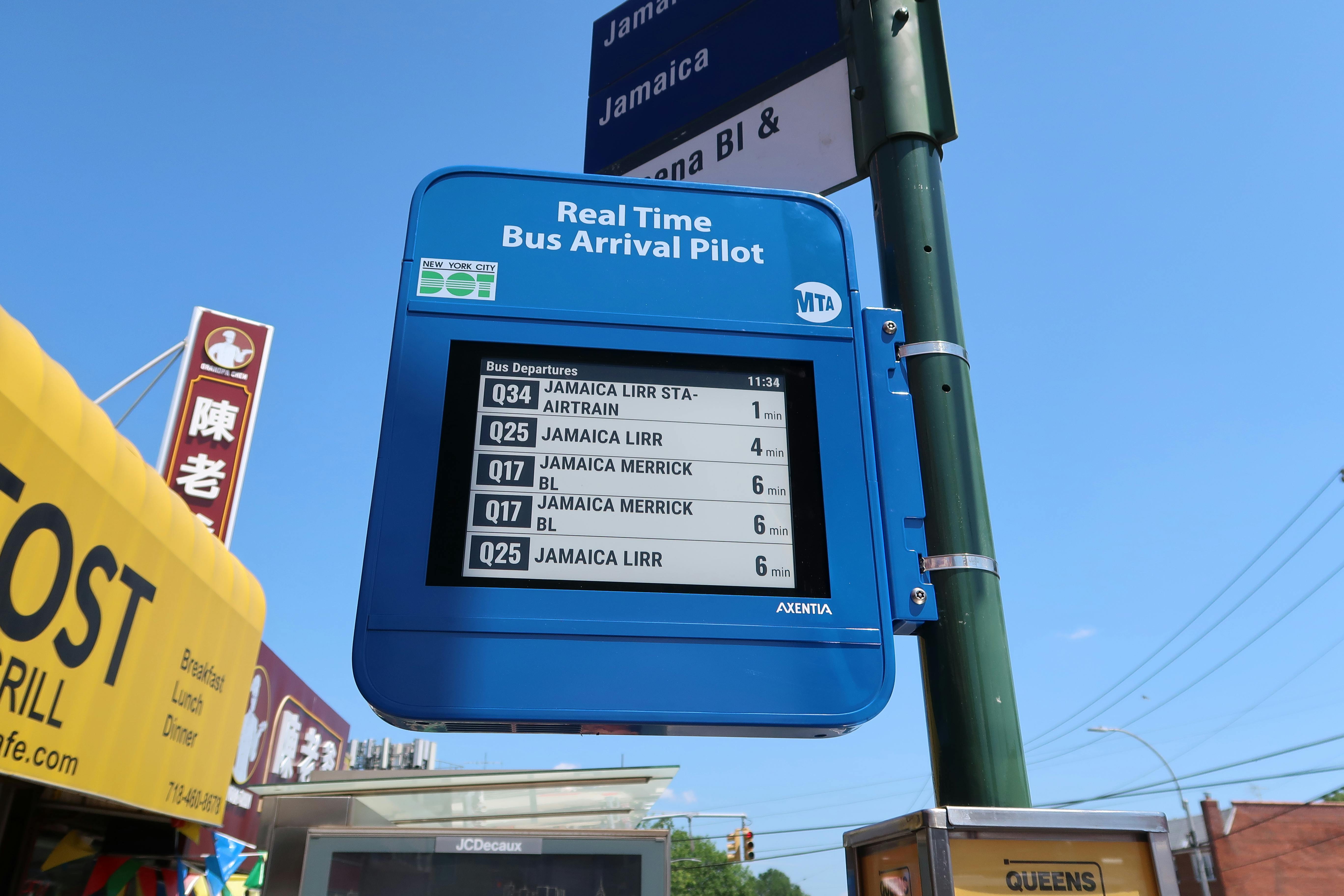 The image displays the Urban Solar e-paper display displaying arrival times for a Queens bus stop.